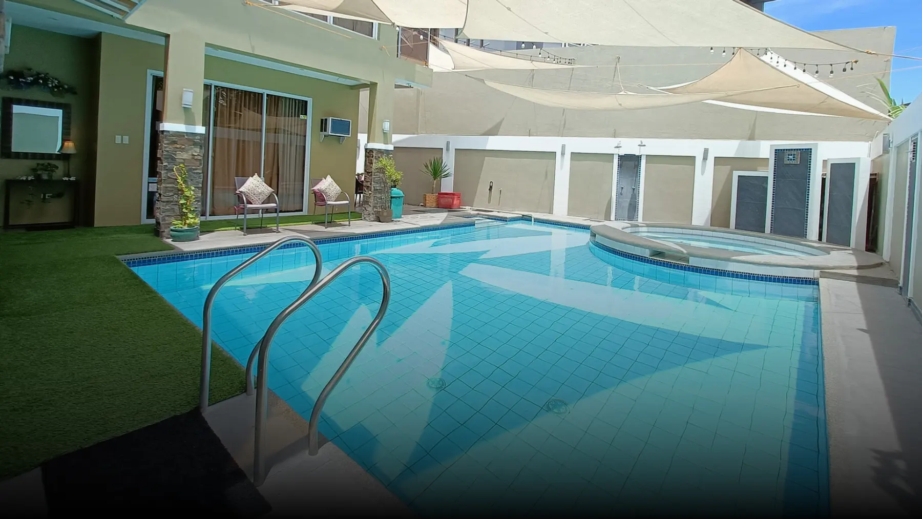 The pool, artificial lawn and shade sails in daylight