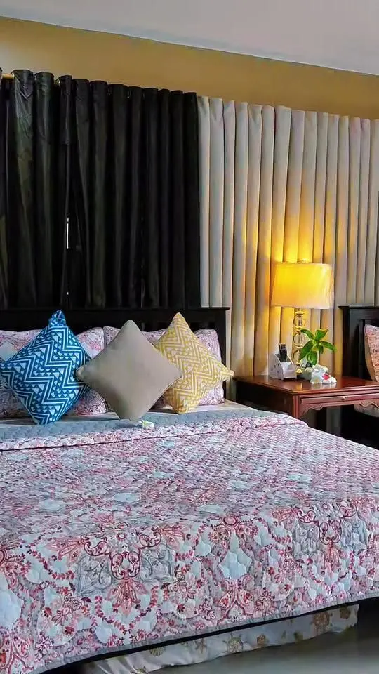 A queen bed with patterned pillows and blackout curtains